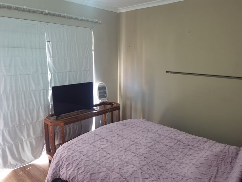 A bedroom featuring laminate flooring and a sliding door with a curtain track, providing access to natural light.