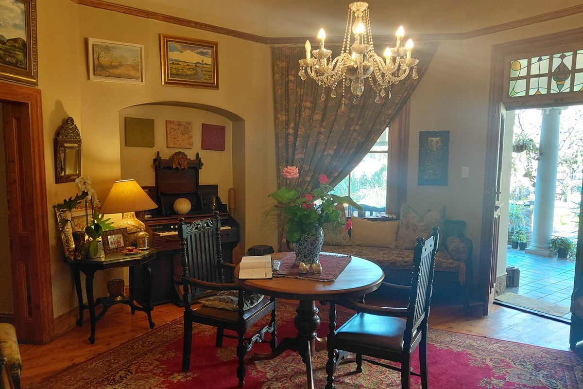 A character-filled living room featuring polished hardwood floors, a classic crystal chandelier, and a charming stained glass transom above the entrance door.