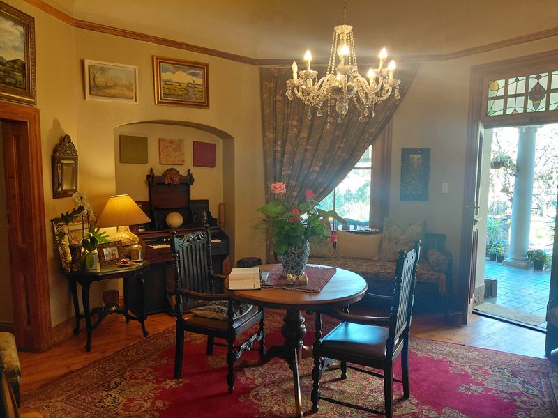 A character-filled living room featuring polished hardwood floors, a classic crystal chandelier, and a charming stained glass transom above the entrance door.