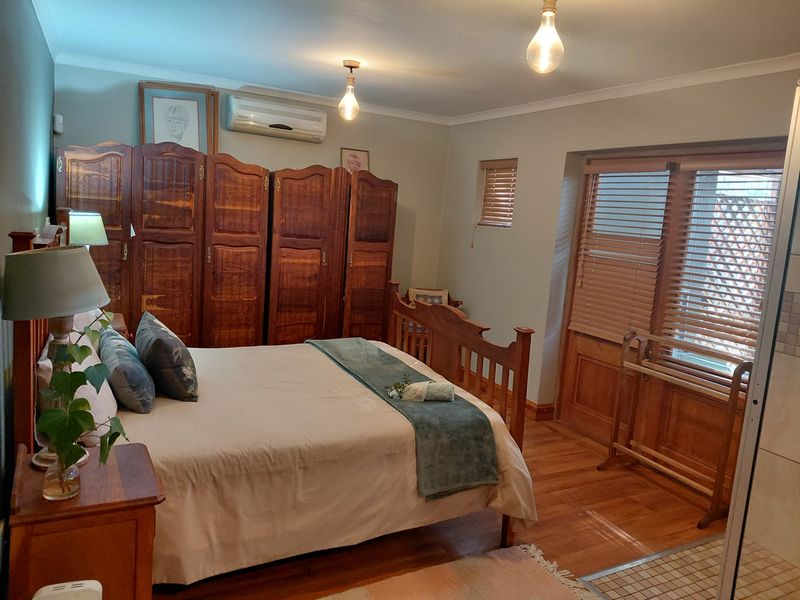 A bedroom featuring timber flooring, split-system air conditioning, and timber blinds, offering a functional space with traditional finishes.