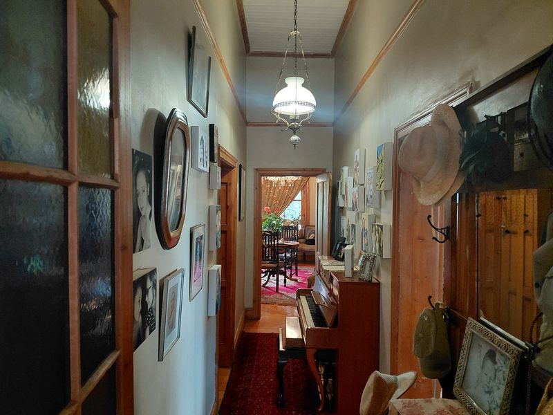 A traditional hallway featuring timber door frames, stained glass detailing, and a classic pendant light fixture, leading through to an adjoining living space.