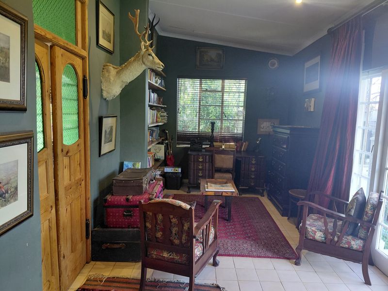 A study or home office featuring built-in shelving, tiled flooring, and natural light through a window and glass-paneled door.