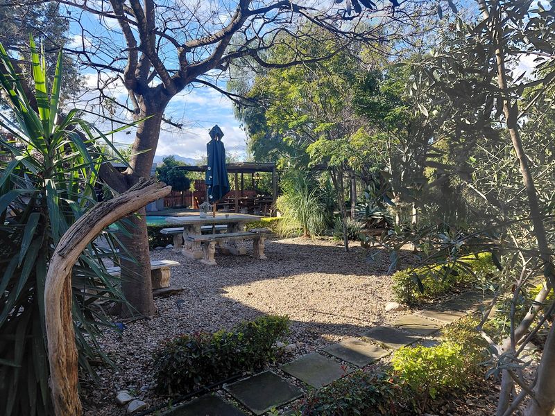 A landscaped garden area featuring gravel pathways, stone paving, and mature trees, providing a natural outdoor setting.