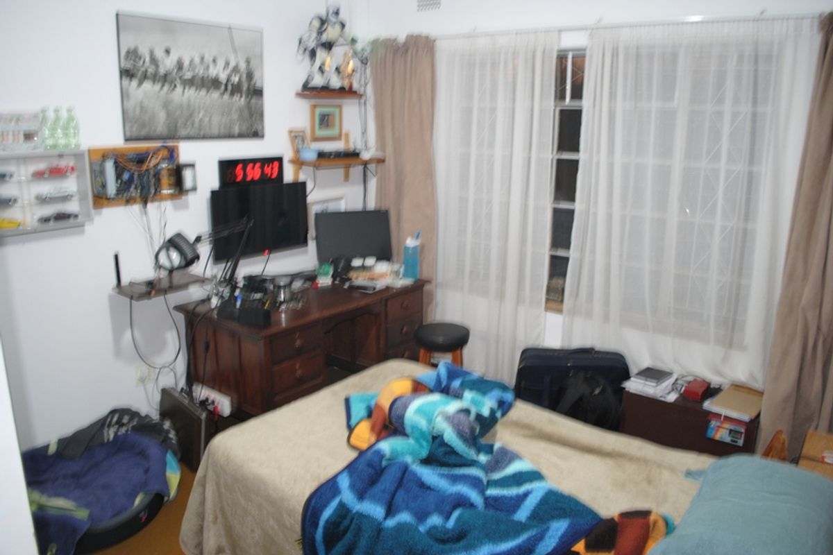 A bedroom featuring standard window treatments with security burglar bars, providing a functional space for rest.