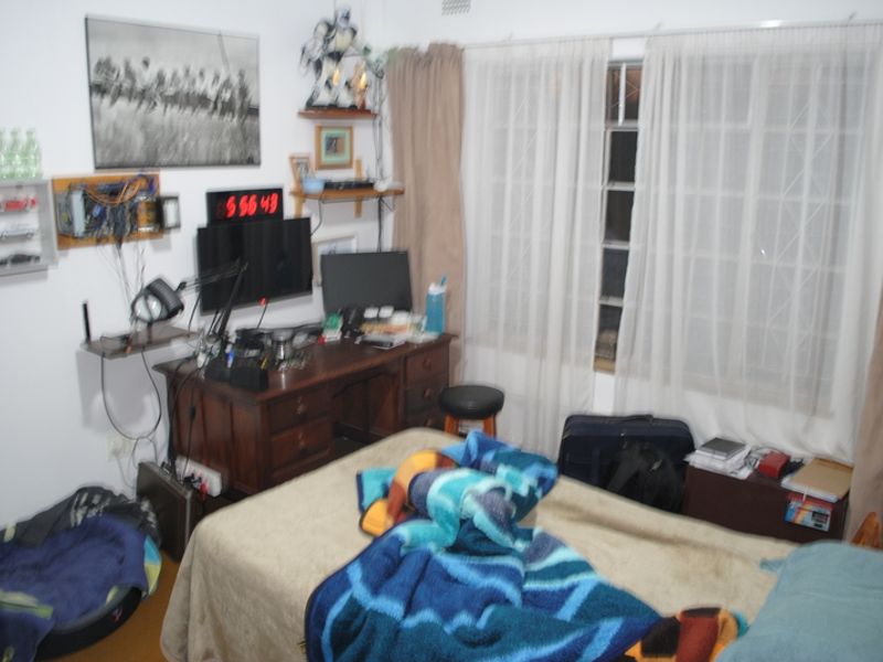 A bedroom featuring standard window treatments with security burglar bars, providing a functional space for rest.
