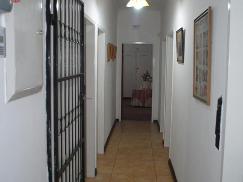 A functional interior hallway featuring tiled flooring and a security gate, providing access to various rooms within the property.