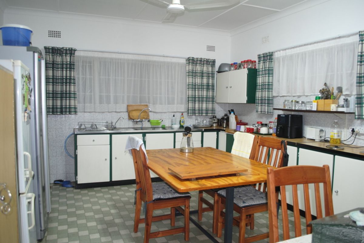 A functional kitchen featuring dated cabinetry, a double sink, and tiled flooring, offering potential for modernization and renovation.