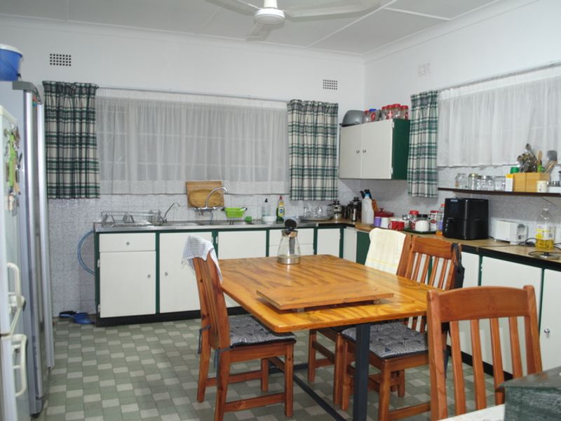 A functional kitchen featuring dated cabinetry, a double sink, and tiled flooring, offering potential for modernization and renovation.