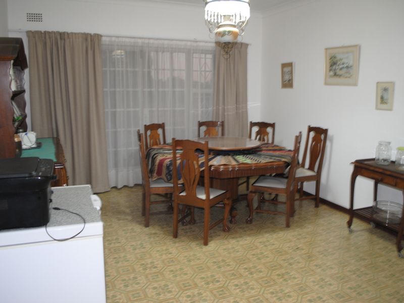 A dining room featuring dated vinyl flooring, a central light fixture, and a sliding glass door leading to the exterior.