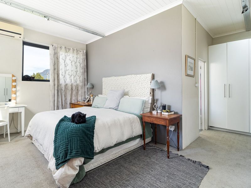 A well-lit bedroom featuring built-in cupboards, a tongue and groove ceiling, and an air conditioning unit, offering a comfortable and functional living space.