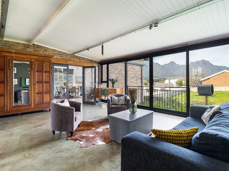 Spacious living area featuring polished concrete floors, exposed brick walls, and large sliding glass doors offering scenic mountain views.
