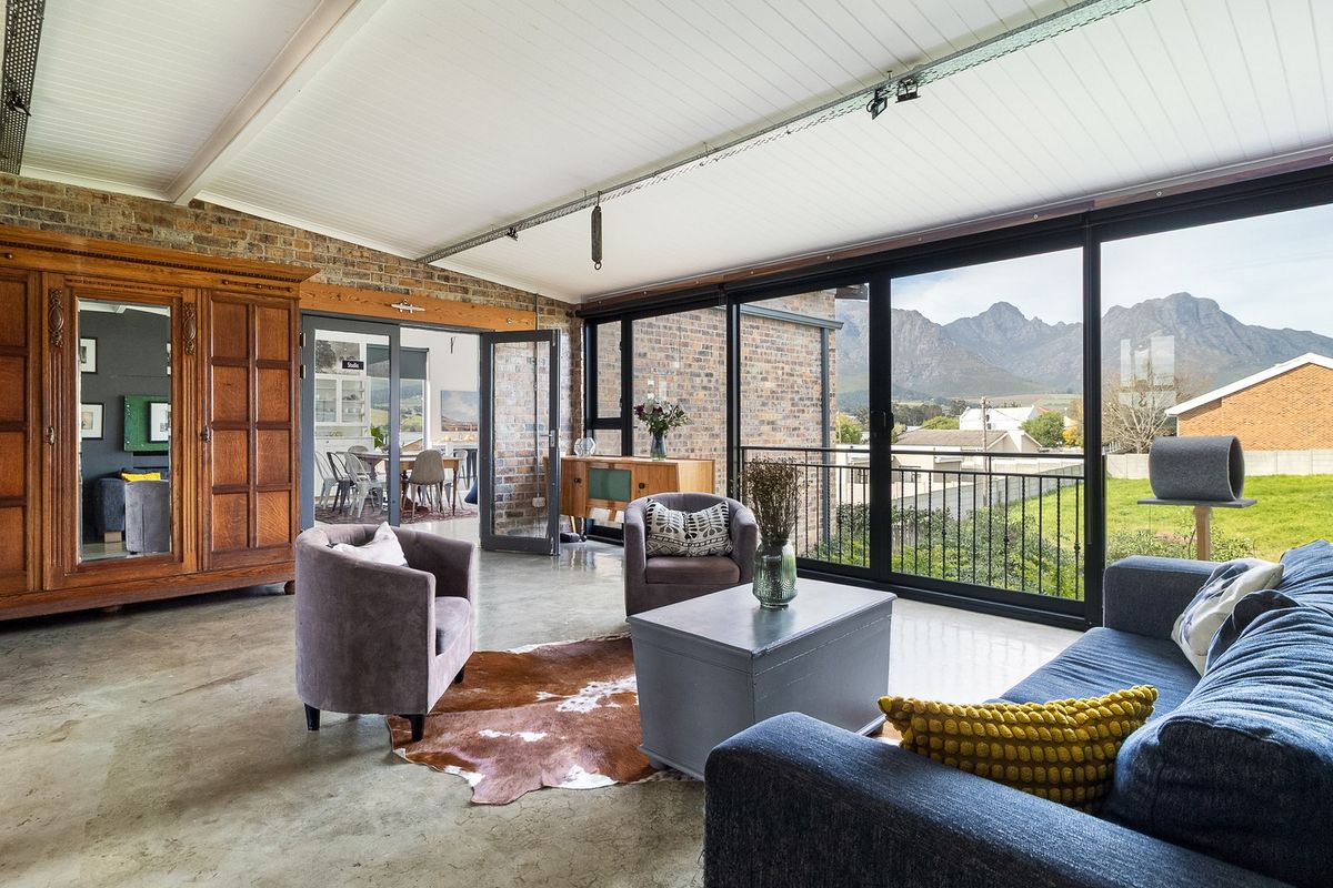 Spacious living area featuring polished concrete floors, exposed brick walls, and large sliding glass doors offering scenic mountain views.