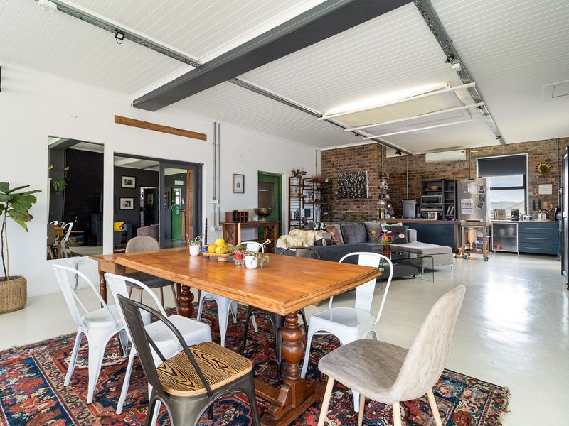 Spacious open-plan living and dining area featuring industrial-style exposed brick walls, steel beams, and polished epoxy flooring with a modern aesthetic.