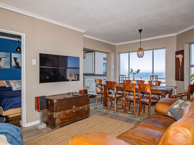 Spacious open-plan living and dining area featuring laminate flooring, large sliding glass doors with ocean views, and neutral wall finishes.