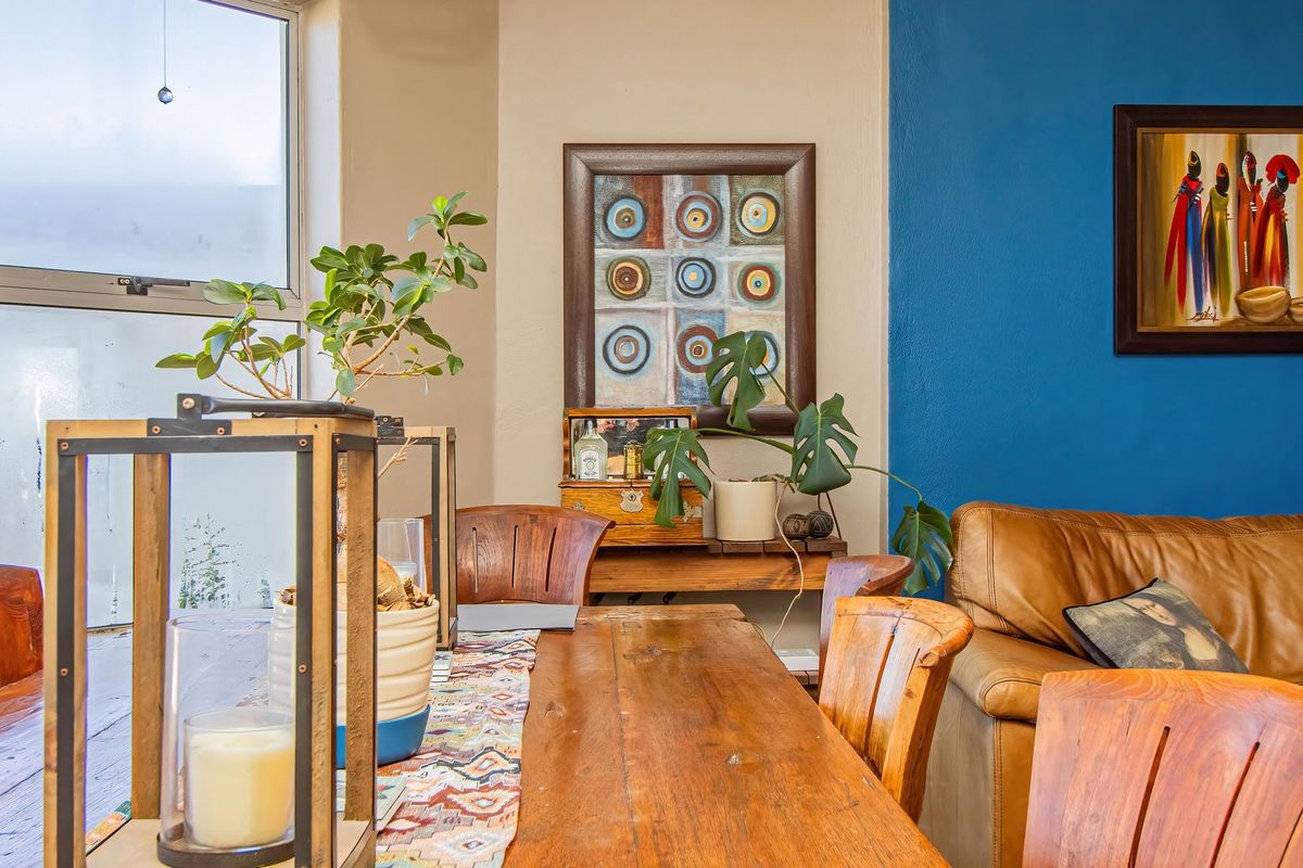 A living area featuring a large window with aluminium frames and a bold blue accent wall, providing a bright and characterful space.