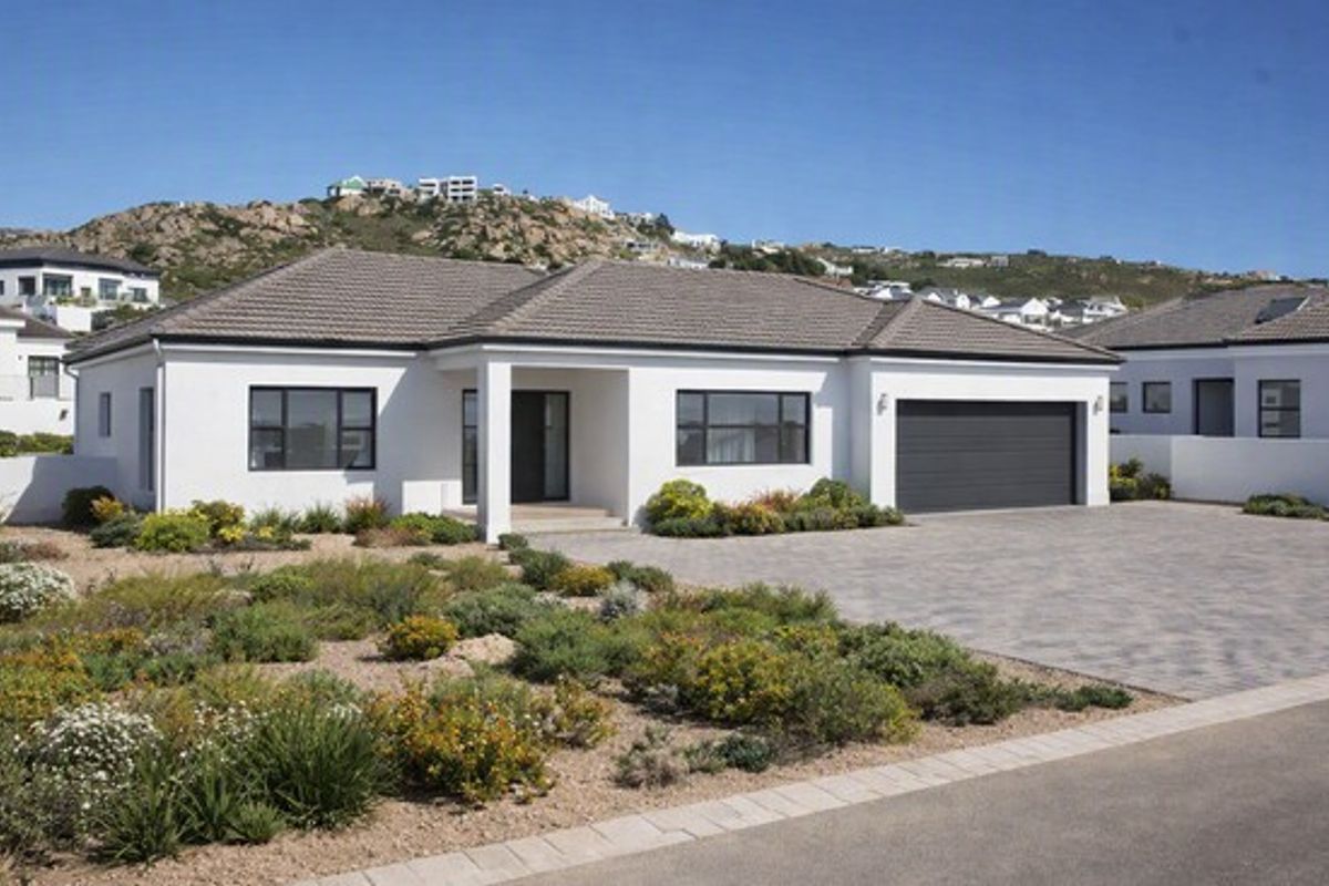 Modern single-story residential home featuring a tiled roof, paved driveway, double garage, and well-maintained landscaped garden in a quiet estate setting.