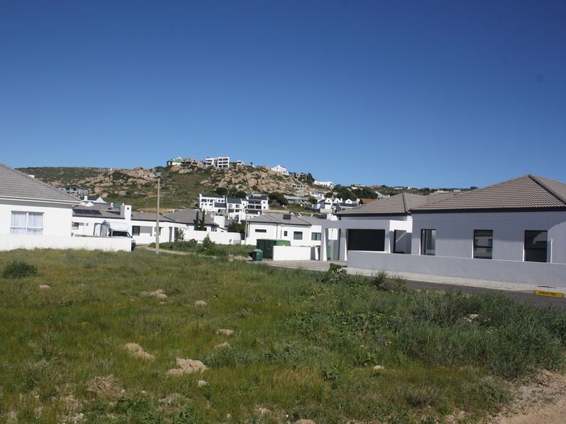 A view of a vacant residential plot situated in a developed neighborhood with paved access and surrounding residential properties.
