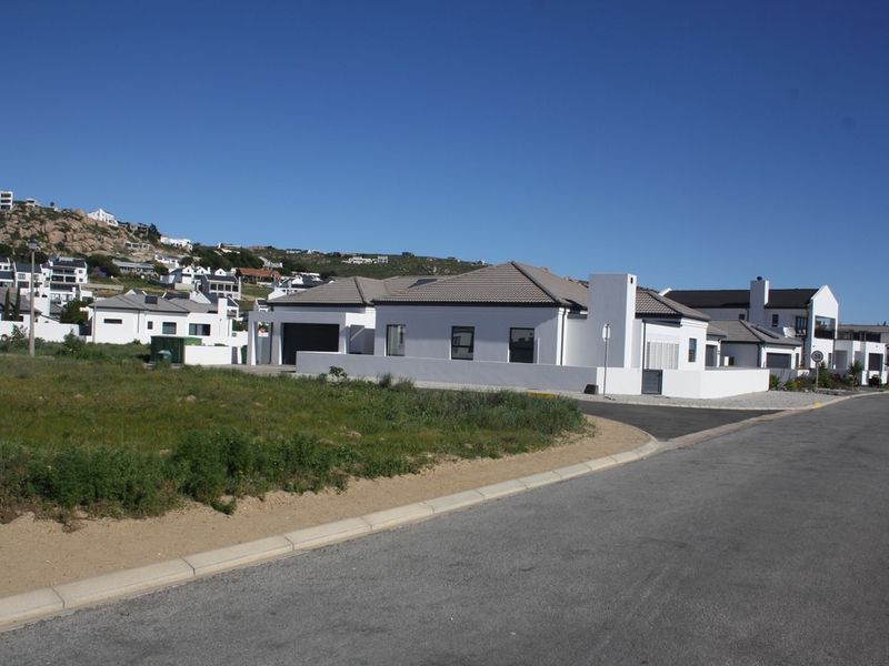 A view of a modern residential property with a paved driveway and tiled roof, situated in a developed coastal estate.