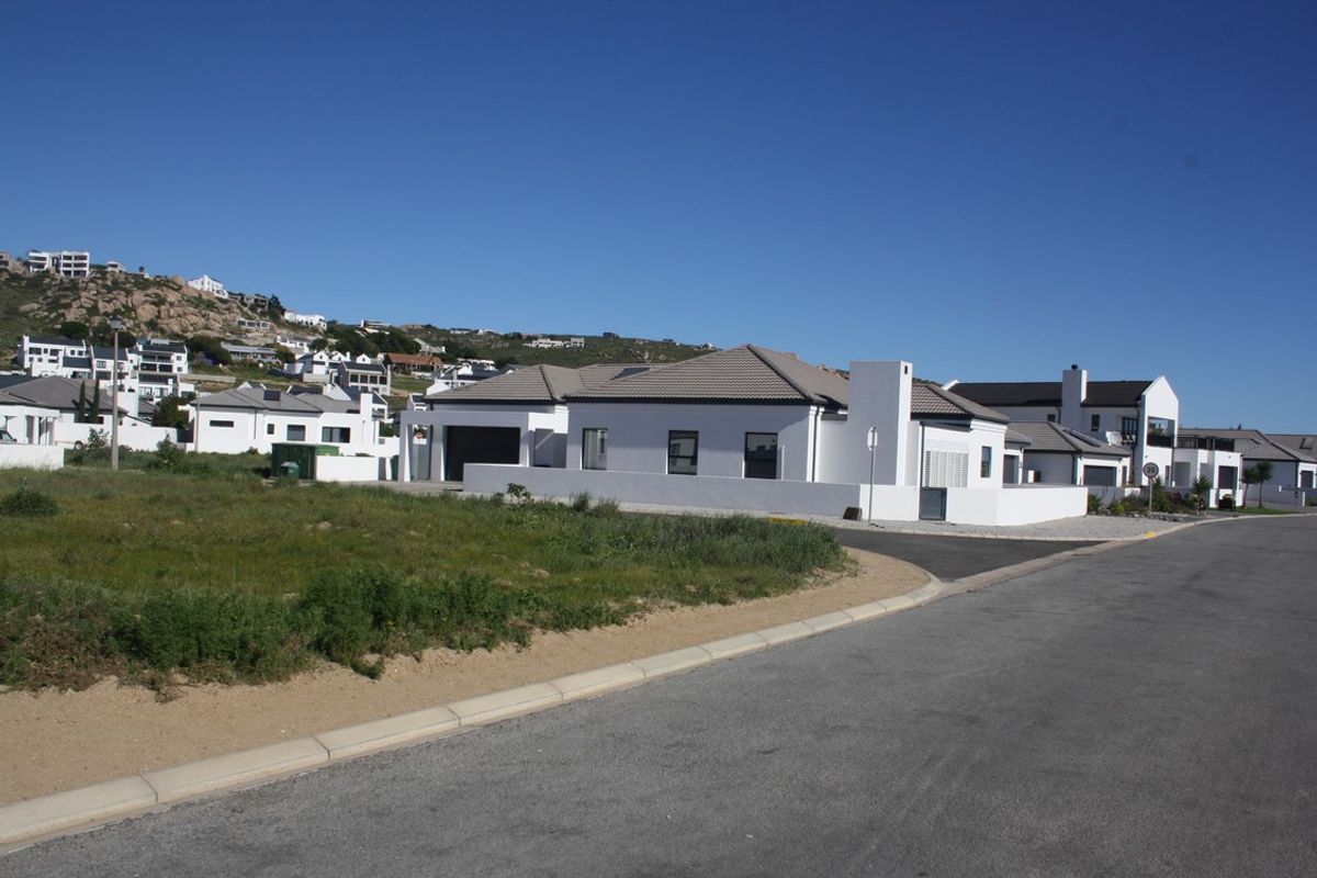 A view of a modern residential property with a paved driveway and tiled roof, situated in a developed coastal estate.