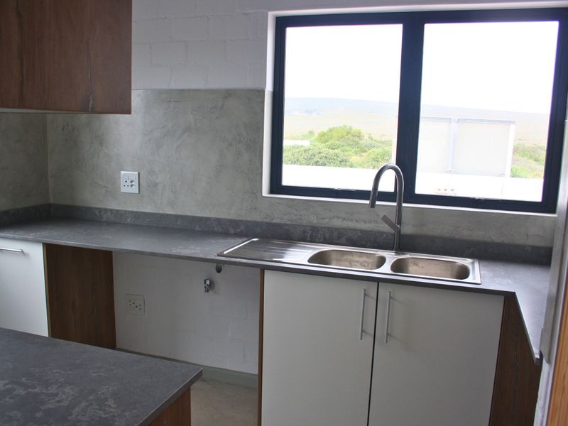Modern kitchen featuring sleek cabinetry, durable laminate countertops, a double bowl sink with a contemporary mixer tap, and a scenic window view.