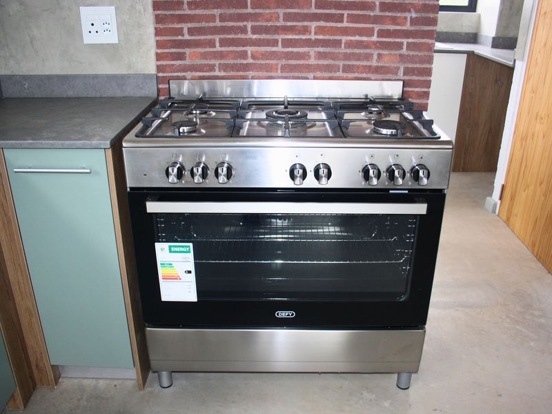 Modern kitchen featuring a stainless steel gas stove and oven, complemented by exposed brick detailing and contemporary cabinetry.