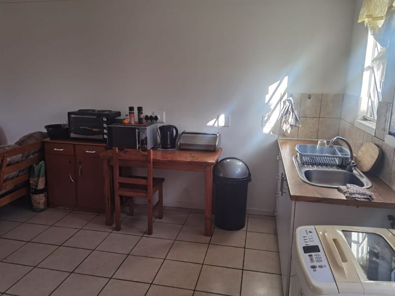 A functional kitchen area featuring tiled flooring, a stainless steel sink, and built-in cabinetry with a tiled splashback.
