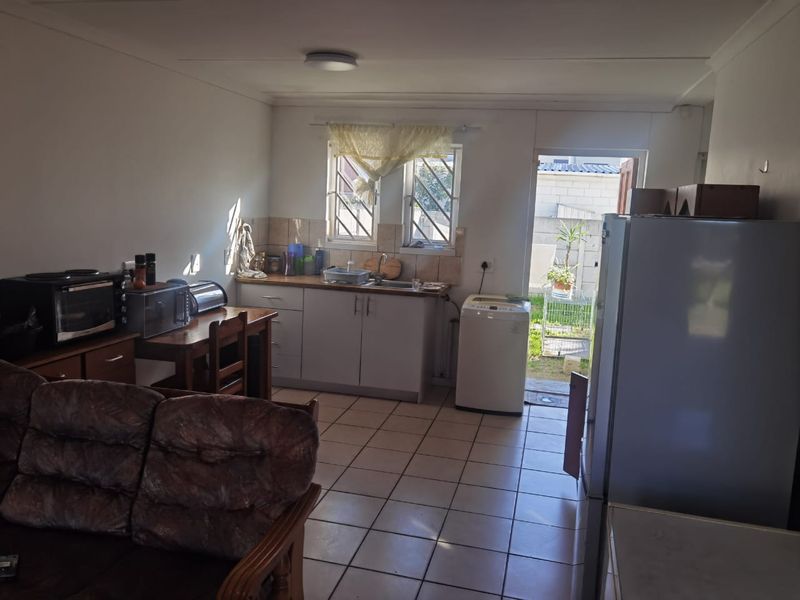 Open plan kitchen and living area featuring tiled flooring, built-in cabinetry, and direct access to the rear exterior space.