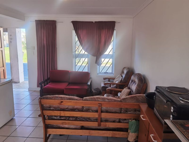 Open plan living area featuring tiled flooring and security bars on windows, with direct access to the exterior.