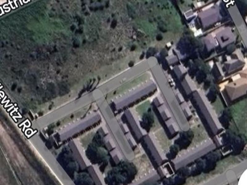 Aerial view of a residential complex and adjacent vacant land parcel situated at the intersection of local roads.
