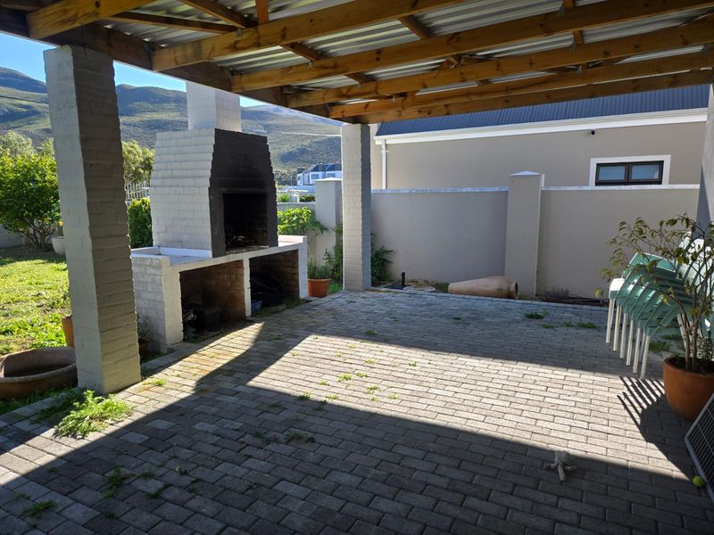Covered outdoor patio featuring a built-in brick braai, paved flooring, and timber roof structure, ideal for outdoor entertaining.