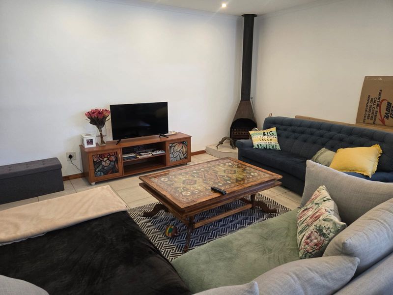 A comfortable living room featuring tiled flooring and a prominent freestanding fireplace, providing a cozy atmosphere for relaxation.