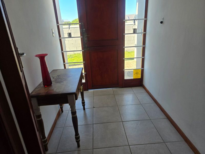 Entrance foyer featuring tiled flooring and a timber front door with integrated security gate.