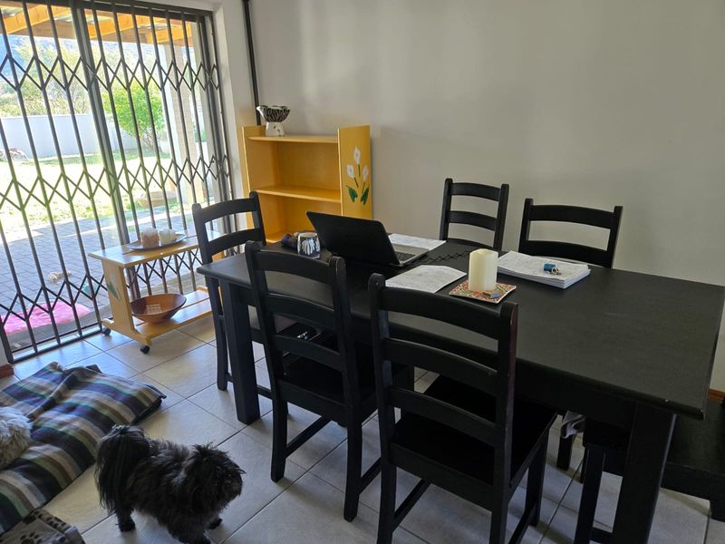 A dining area featuring tiled flooring and a sliding glass door with a security gate, providing direct access to the outdoor patio area.