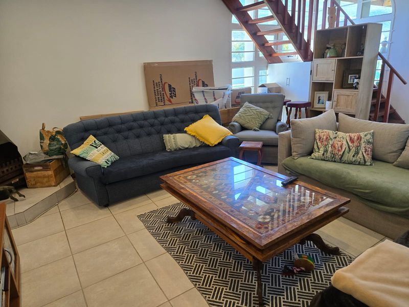 A living room featuring tiled flooring, a built-in fireplace, and an open wooden staircase leading to the upper level.
