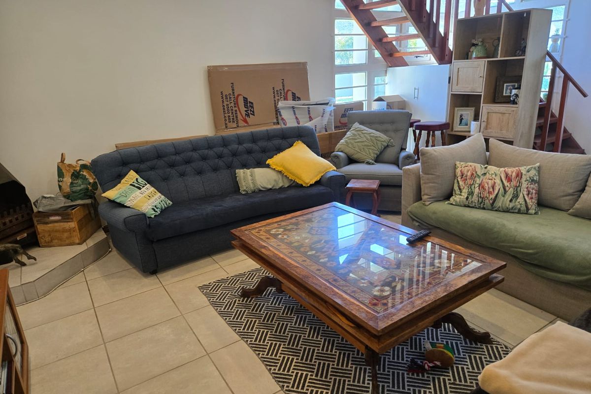 A living room featuring tiled flooring, a built-in fireplace, and an open wooden staircase leading to the upper level.