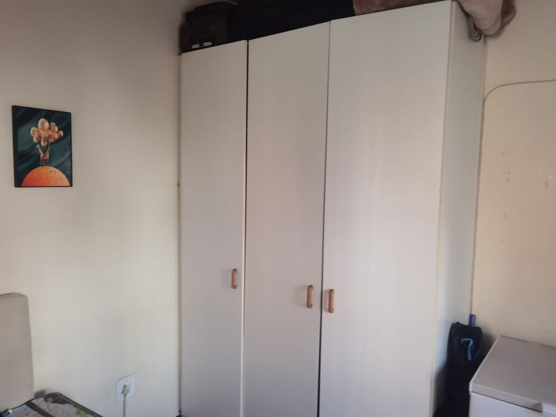 A bedroom featuring a white built-in wardrobe with wooden handles, providing functional storage space.