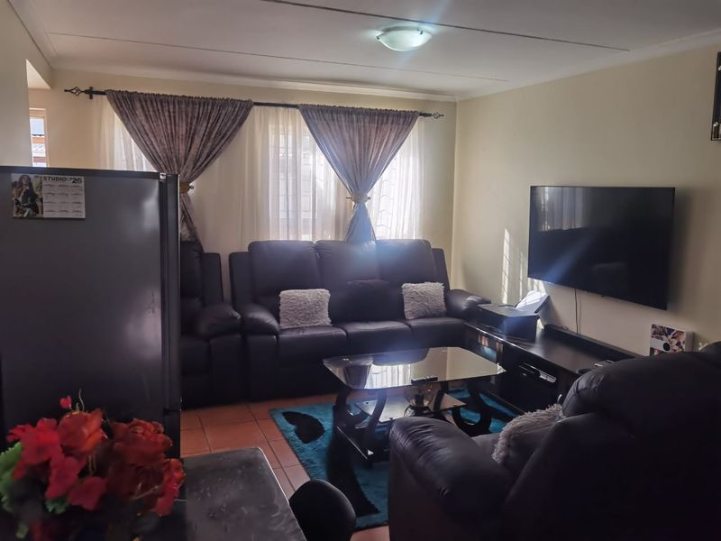 A comfortable living room featuring tiled flooring and a central ceiling light fixture, providing a functional space for relaxation.