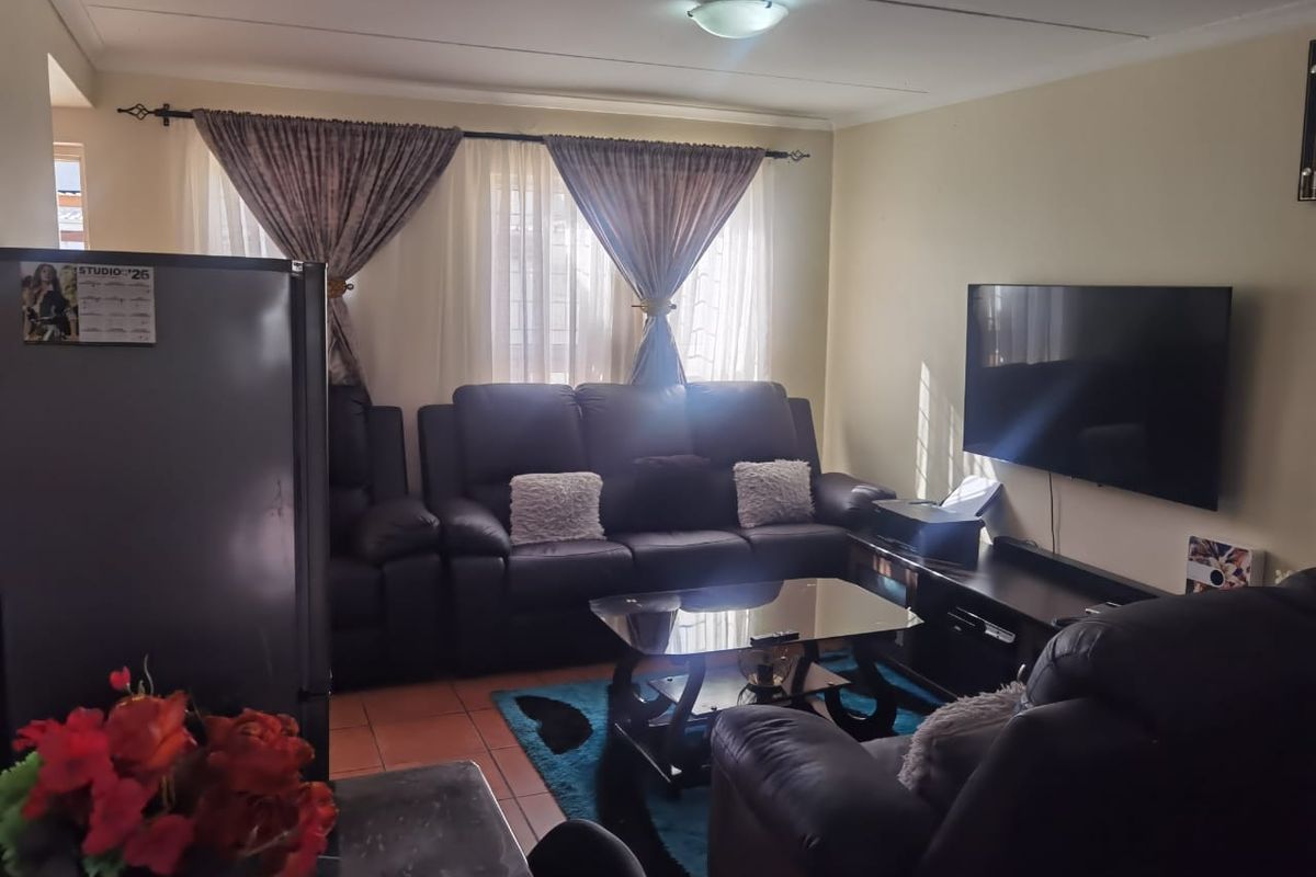A comfortable living room featuring tiled flooring and a central ceiling light fixture, providing a functional space for relaxation.