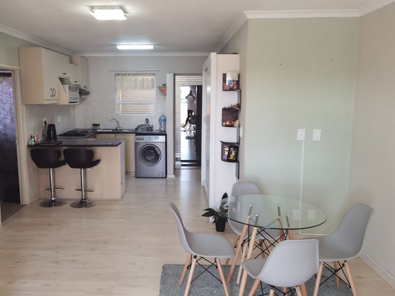 Open-plan living and kitchen area featuring light laminate flooring, built-in cabinetry, and a functional kitchen layout with integrated appliances.