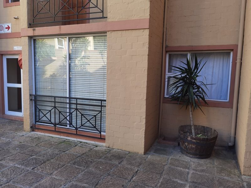 Ground floor patio area featuring stone paving, a sliding glass door with a metal balustrade, and brick exterior wall finishes.