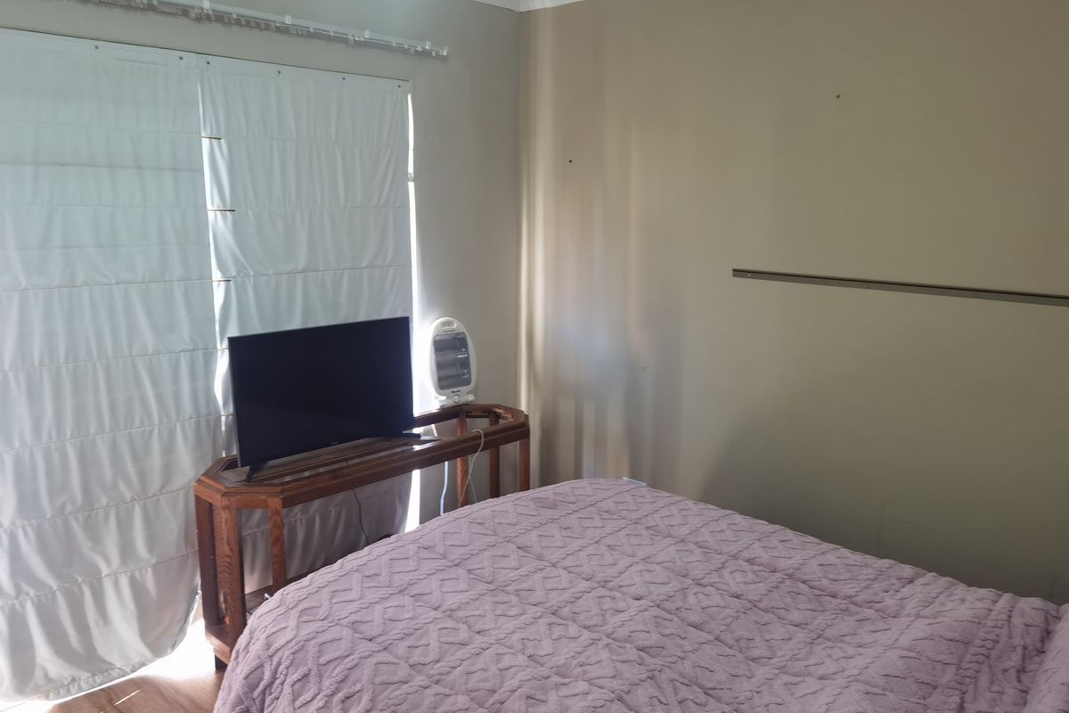 A bedroom featuring laminate flooring and a sliding glass door with a curtain track, providing access to the exterior.