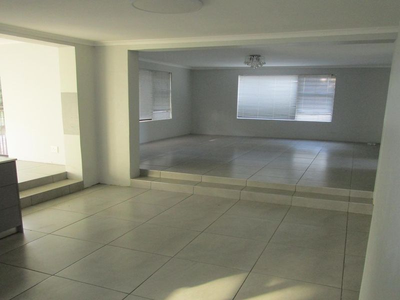 Spacious open-plan living area featuring large format floor tiles, a sunken lounge section, and neutral finishes throughout.