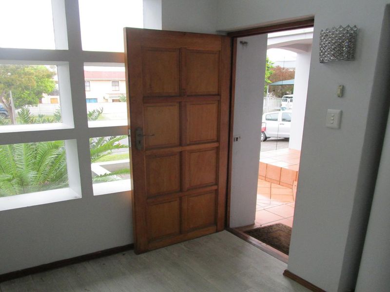 A bright entrance hall featuring a solid timber panelled door and a large grid window, providing a welcoming transition into the home.