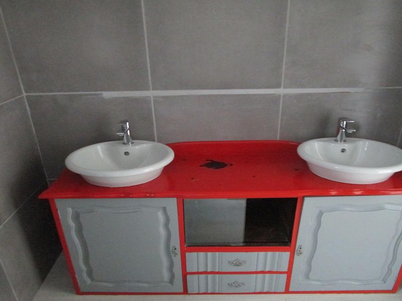 A bathroom vanity area featuring a double basin setup with tiled walls and a custom-painted vanity cabinet.