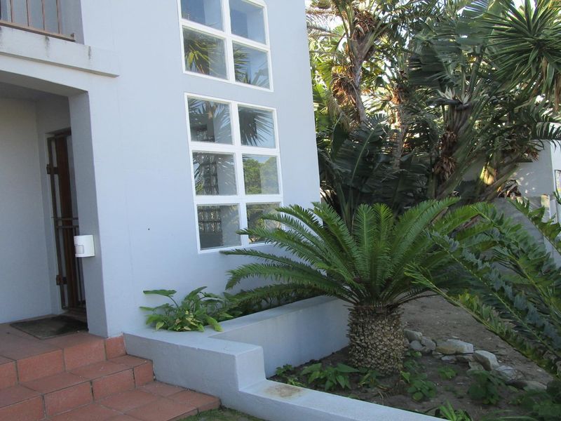 Front entrance area featuring tiled steps, a security gate, and a built-in planter box set against a light-colored exterior facade.