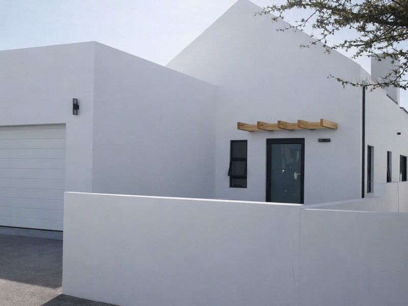 Modern front elevation featuring a clean white facade, integrated garage, timber pergola detail, and a secure boundary wall.
