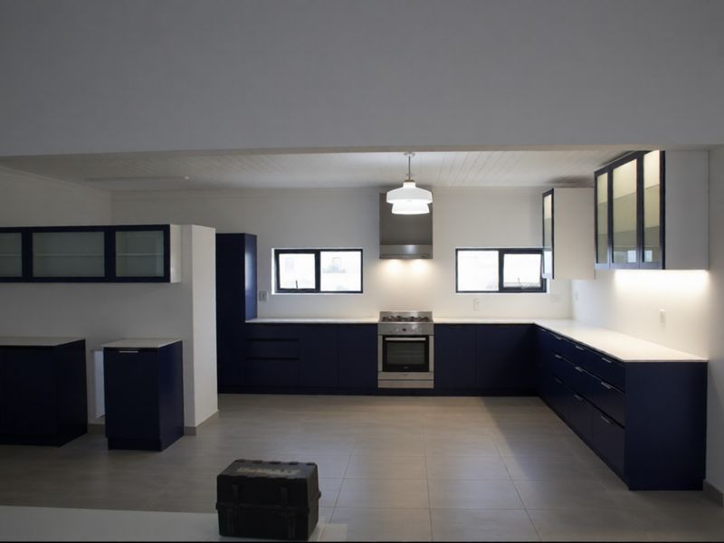 Modern, spacious kitchen featuring dark blue cabinetry, stone countertops, integrated stainless steel appliances, and ample under-cabinet lighting.