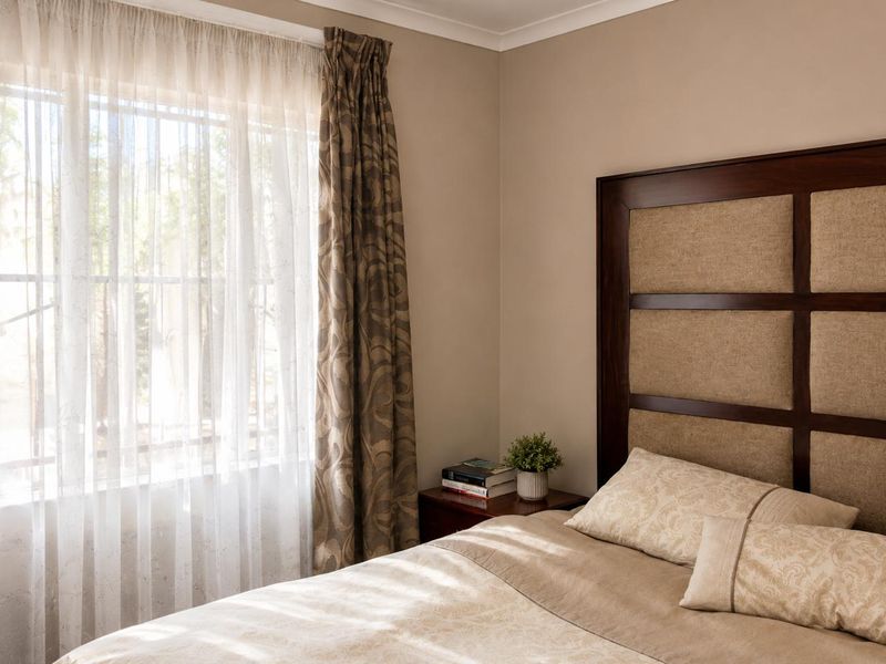 A well-maintained bedroom featuring neutral wall tones, coving, and a large window allowing natural light to enter the space.