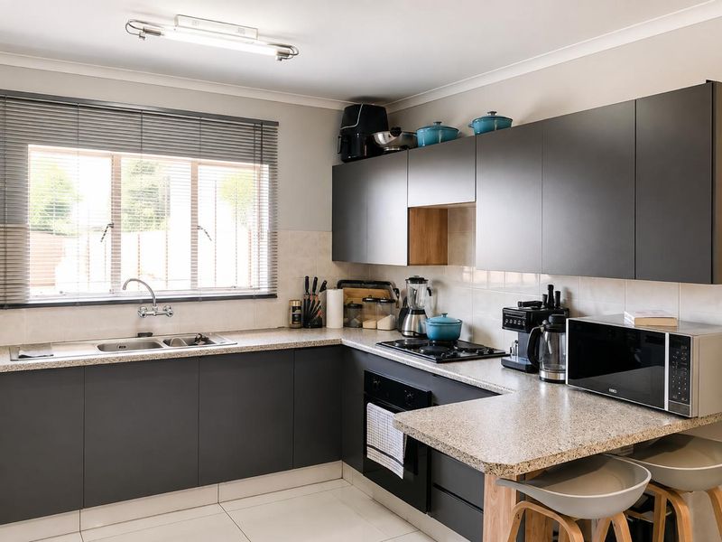 Modern kitchen featuring dark grey cabinetry, granite countertops, built-in oven, gas hob, and a double sink with a window view.
