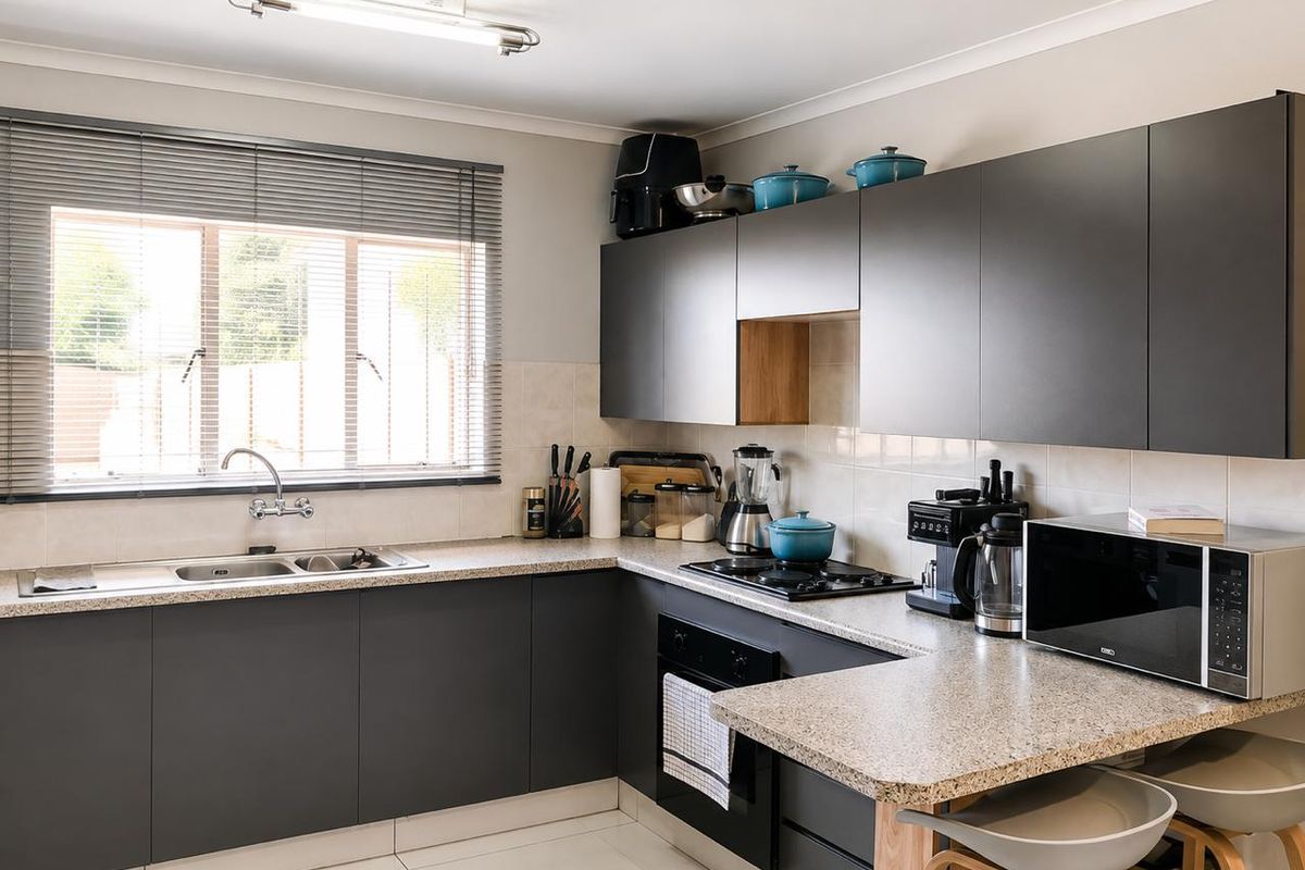 Modern kitchen featuring dark grey cabinetry, granite countertops, built-in oven, gas hob, and a double sink with a window view.